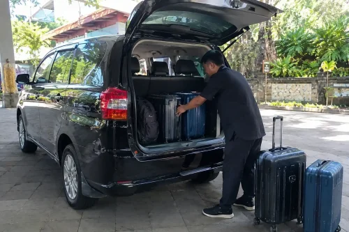 Driver loading bags into car trunk during Bali airport to Sidemen transfer.