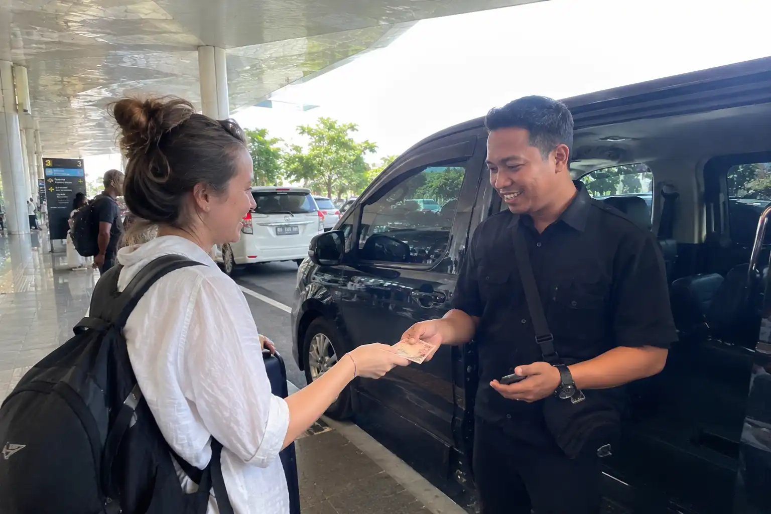 Traveller giving a cash tip to a Bali airport transfer driver
