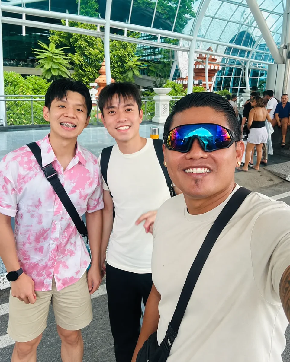 Bali airport transfer driver with travellers at Ngurah Rai Airport arrival hall