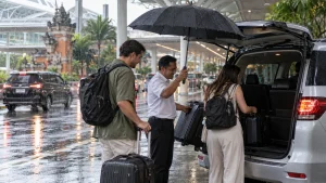 Driver helping airport transfer passengers during tropical rain in Bali.