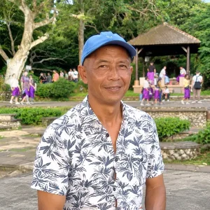 Andik, experienced Bali driver in a blue cap and floral shirt at a Bali tourist spot