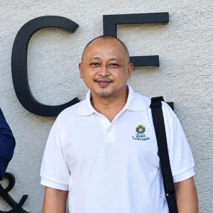 Gede Pande, smiling Bali private driver in a white Bali Touristic polo shirt